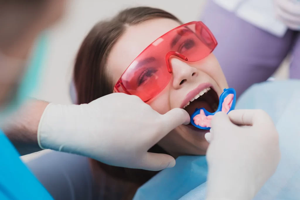 Dentist performing fluoride treatment to female patient.