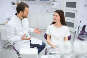 Dentist speaking to a girl in an exam chair.