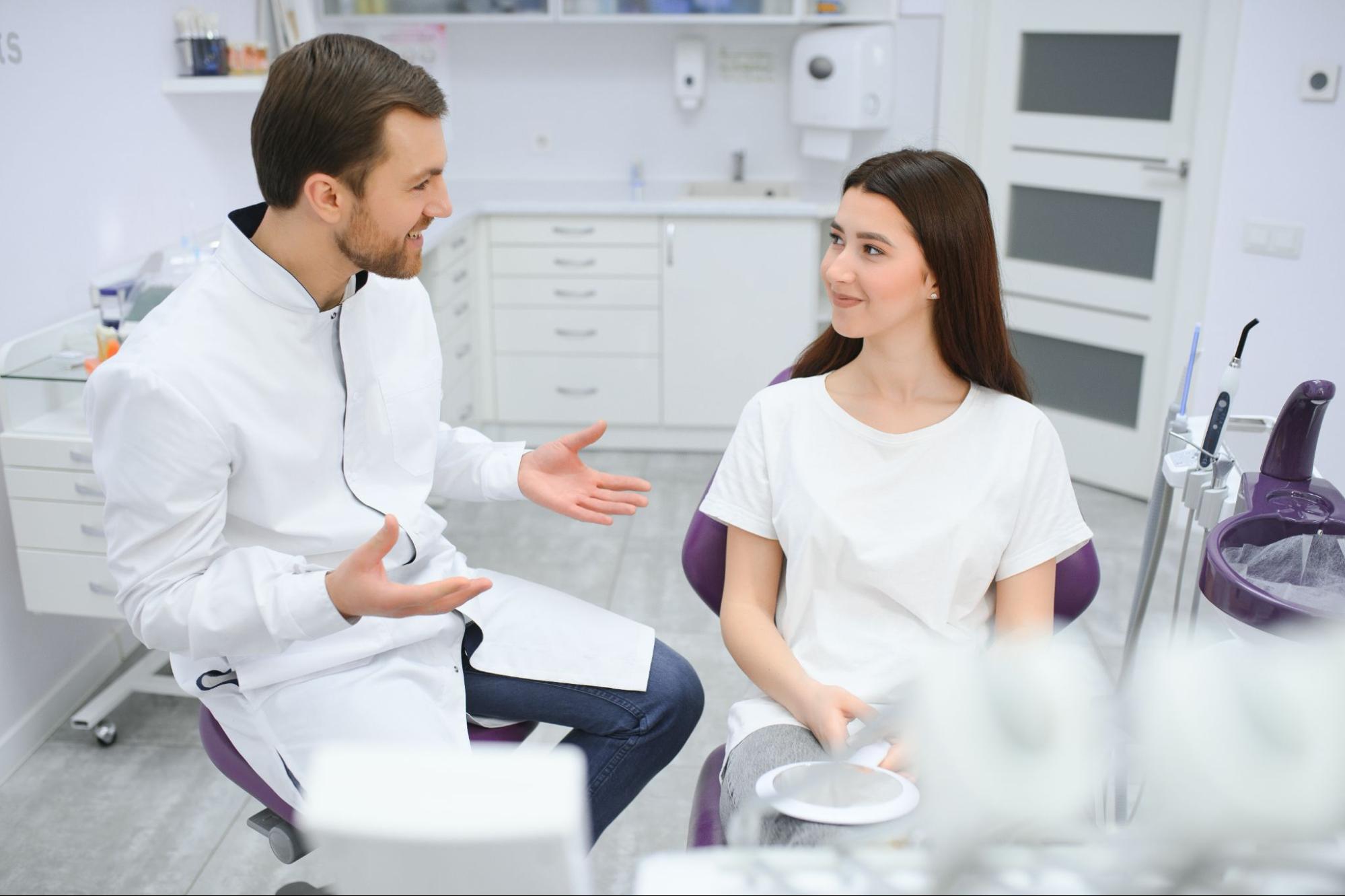 Dentist speaking to a girl in an exam chair.