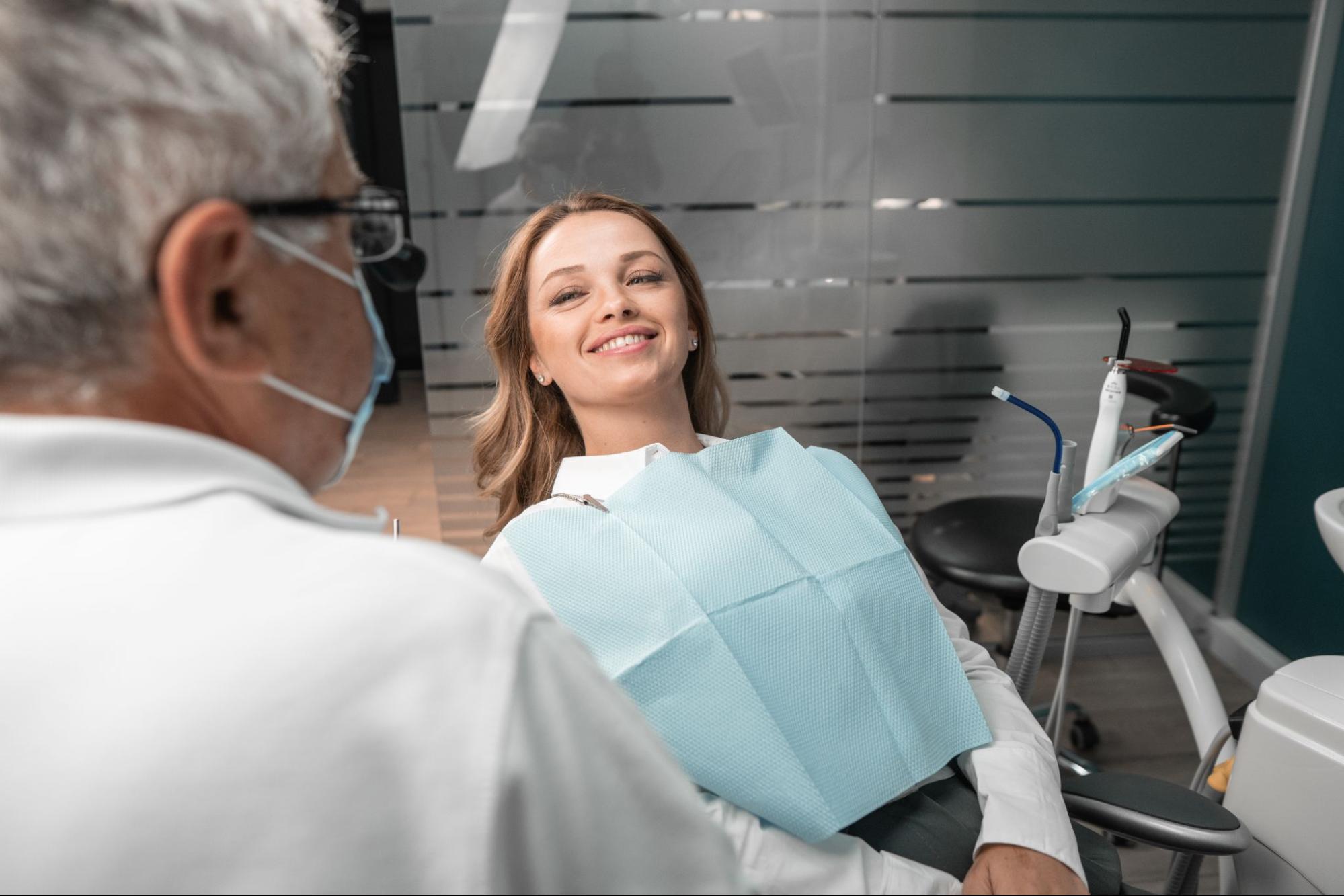 Woman smiling in a dental exam chair next to a dentist.