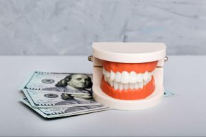 Model of teeth next to money.