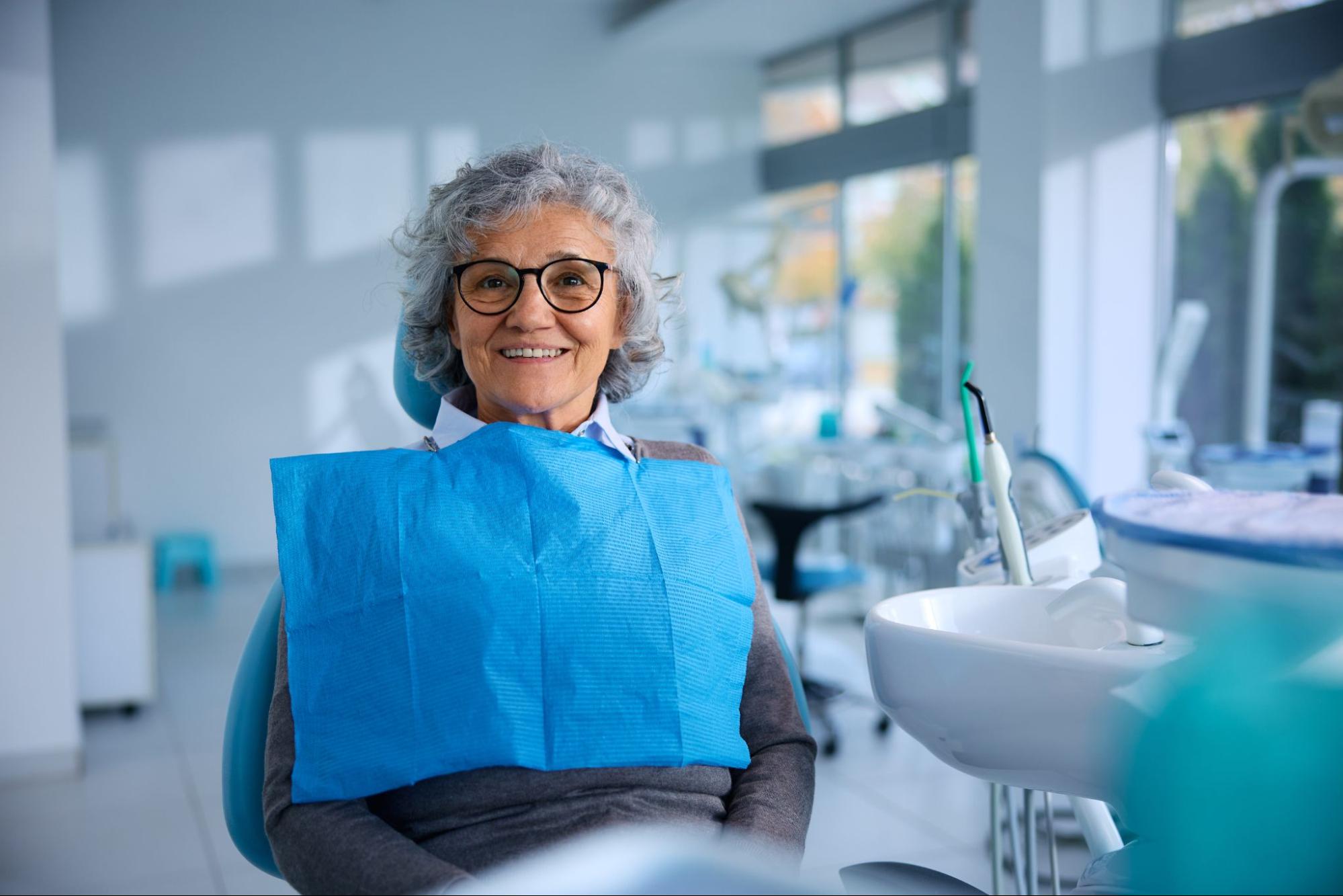 Senior woman in a dental exam chair and smiling.