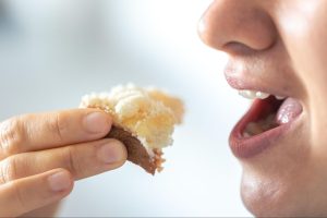 A close-up of a woman eating bread with grated cheese, a soft food choice ideal for comfort and safety after getting a dental filling.