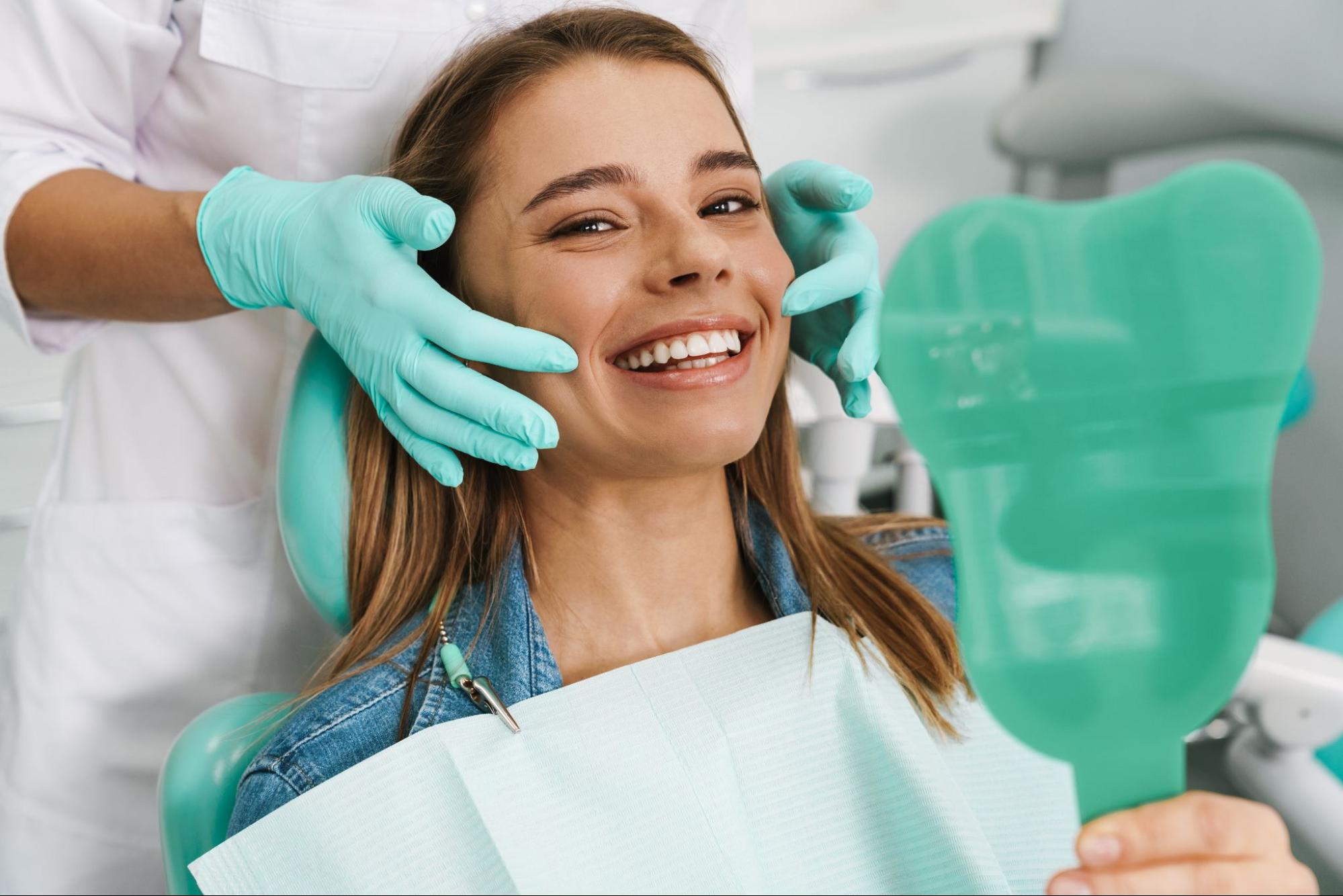 Happy female patient in an exam chair looking into a mirror.