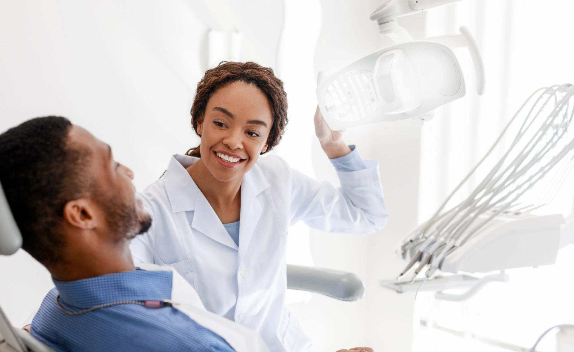 Female dentist next to a male patient in an exam chair.