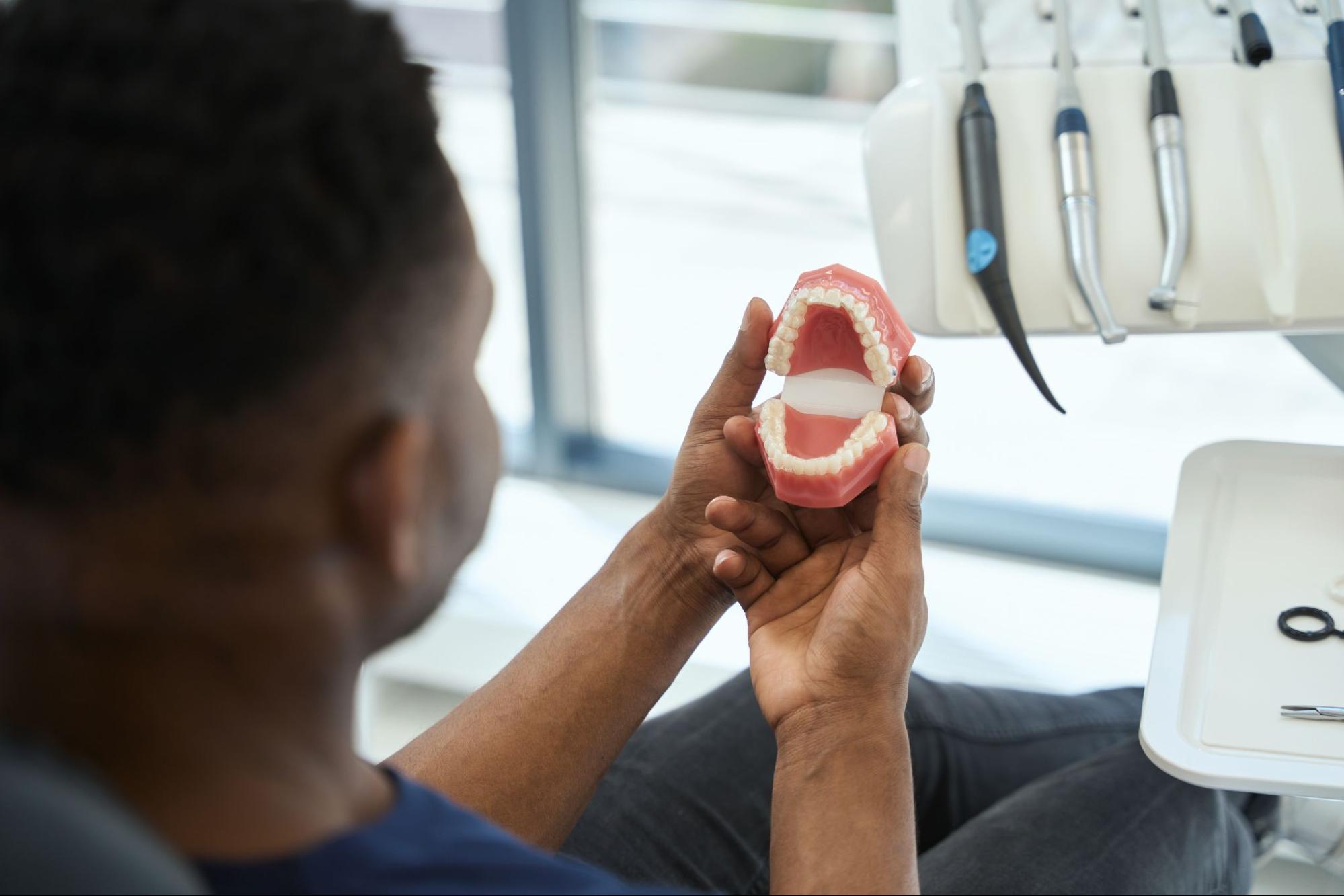 man holding a model of teeth.