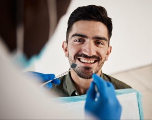 Man smiling at the dentist with gloved hands.