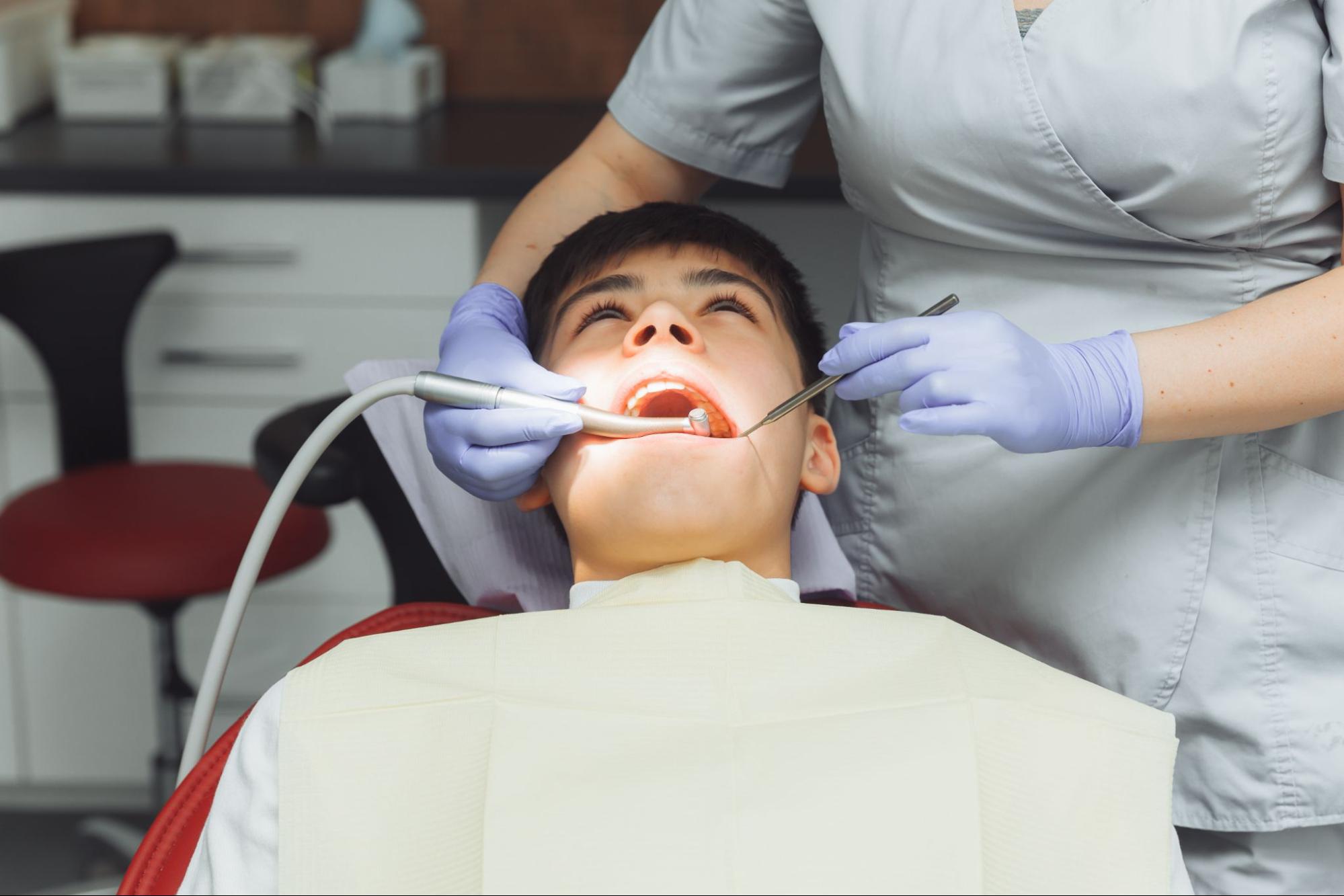 Boy getting his teeth examined by a dentist.