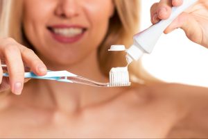 A woman squeezes toothpaste onto her toothbrush.