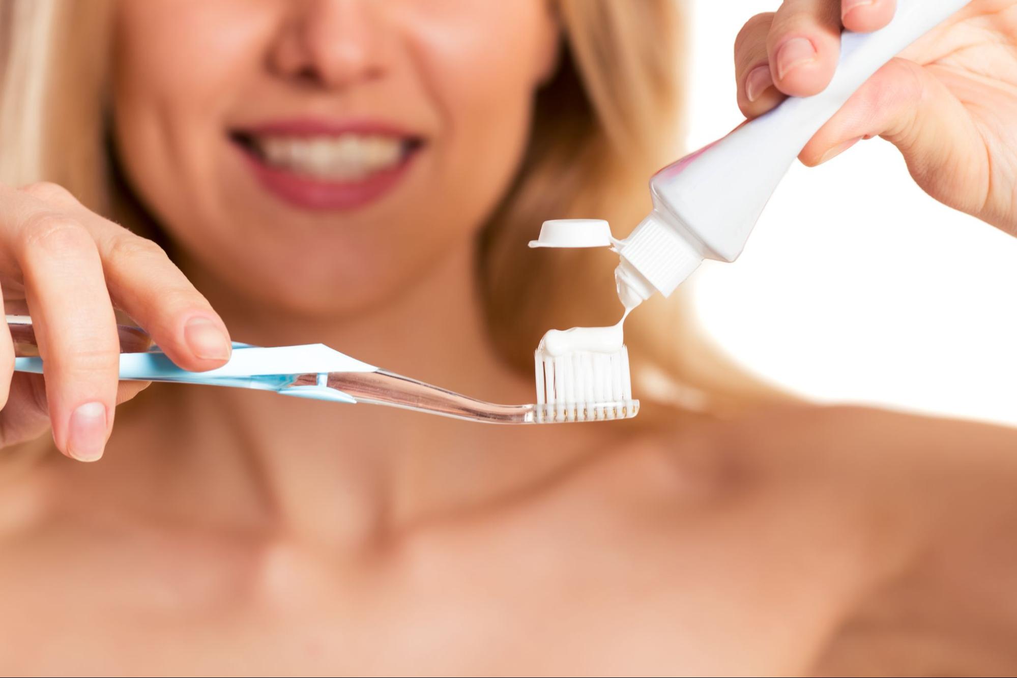 A woman squeezes toothpaste onto her toothbrush.