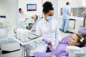 A dentist talks to a young patient to ease anxiety before a routine dental exam.
