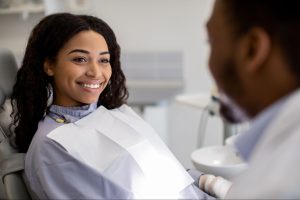 A smiling woman at a dentist appointment is partly shown in the foreground.