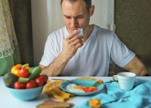 A man finishes a healthy brunch of soft-fried eggs and fresh vegetables.