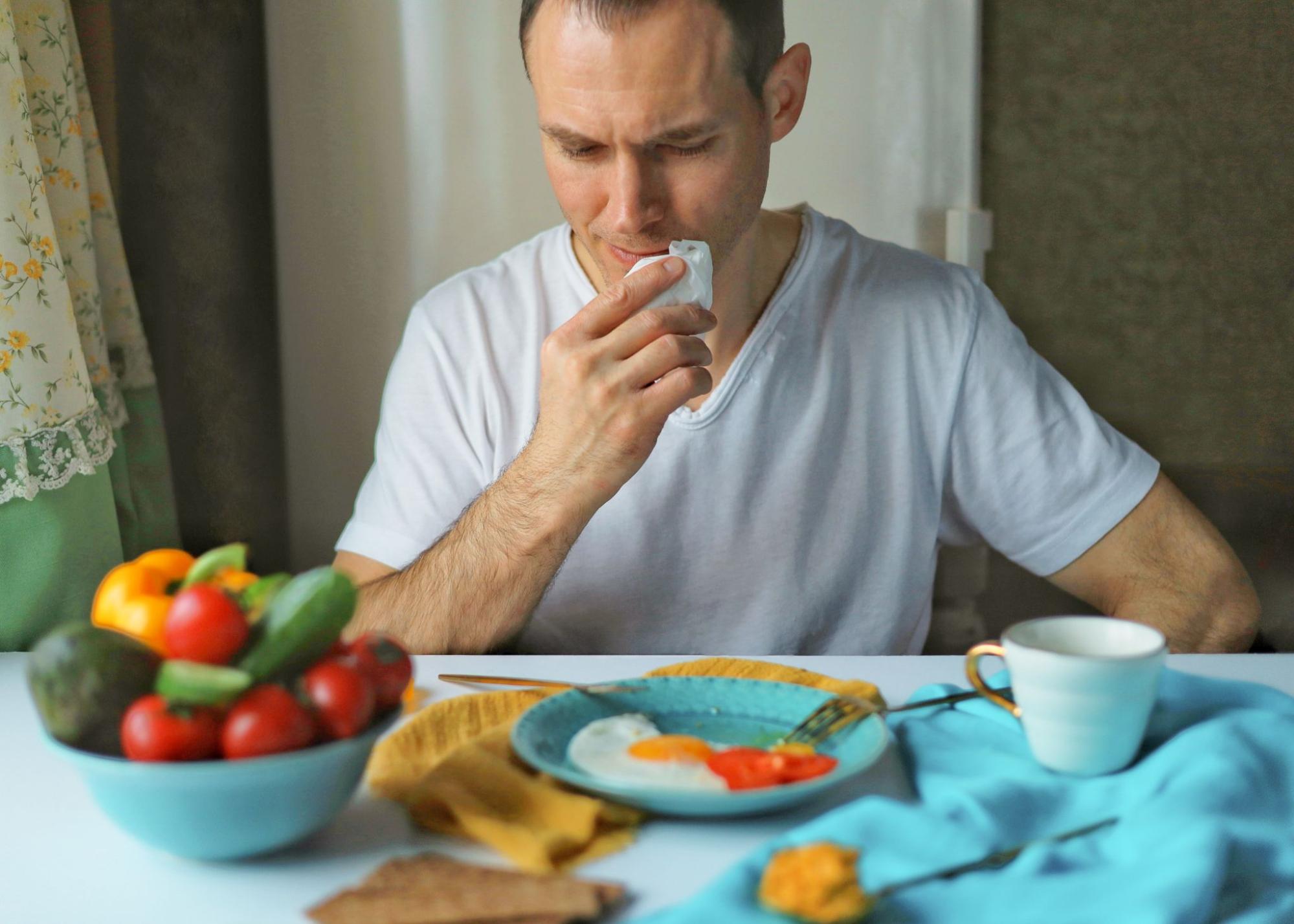 A man finishes a healthy brunch of soft-fried eggs and fresh vegetables.