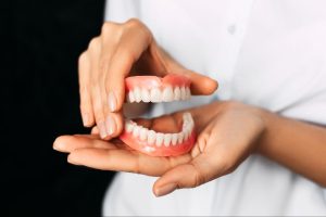 Cropped view of a dentist holding a new set of dentures in her hands.