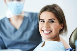 A woman shows bright white teeth after safe whitening treatment.