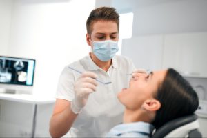 Dentist examining a woman’s teeth in a dental exam chair.