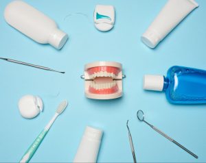 Dental care products and a model showing oral hygiene essentials for root canal recovery on a blue background.